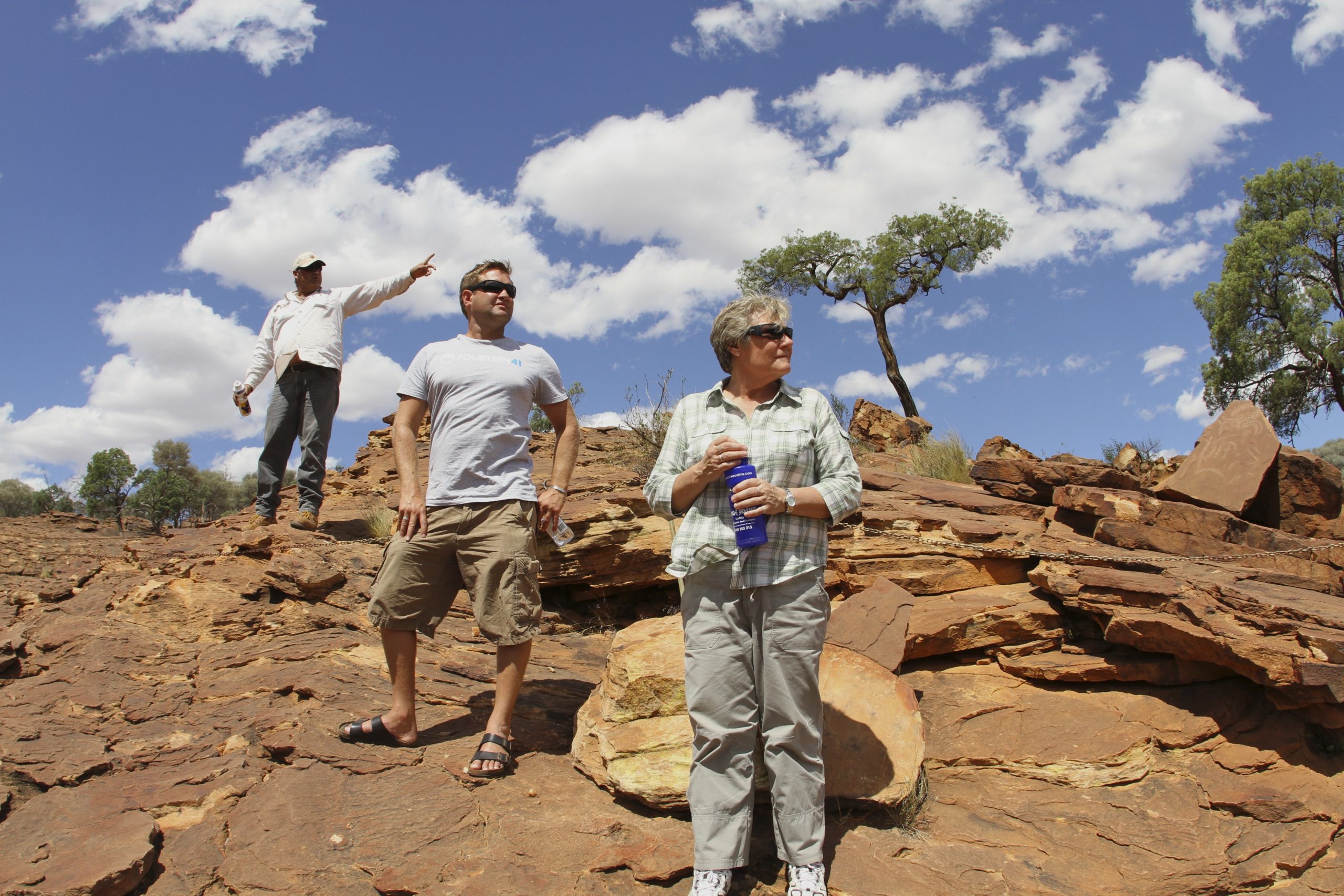 Guide and guests on red rock outcrops at Mutawintji National Park