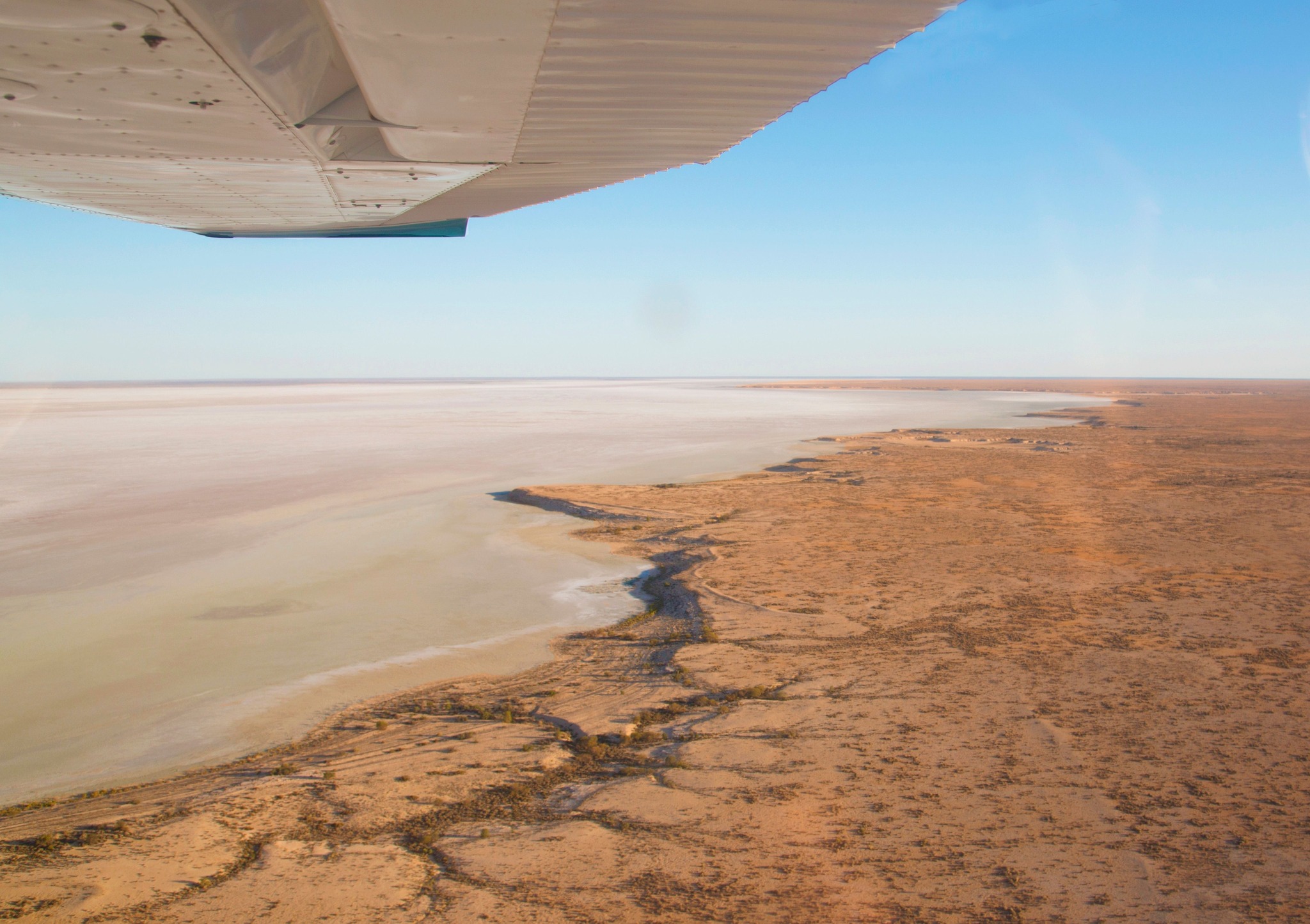 Salt-crusted edge of Lake Eyre seen beneath the wing of a scenic flight