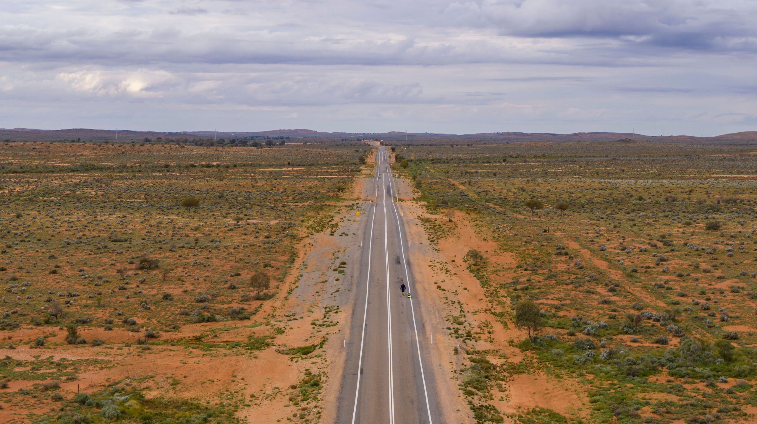 Long straight highway running across saltbush plains to the horizon