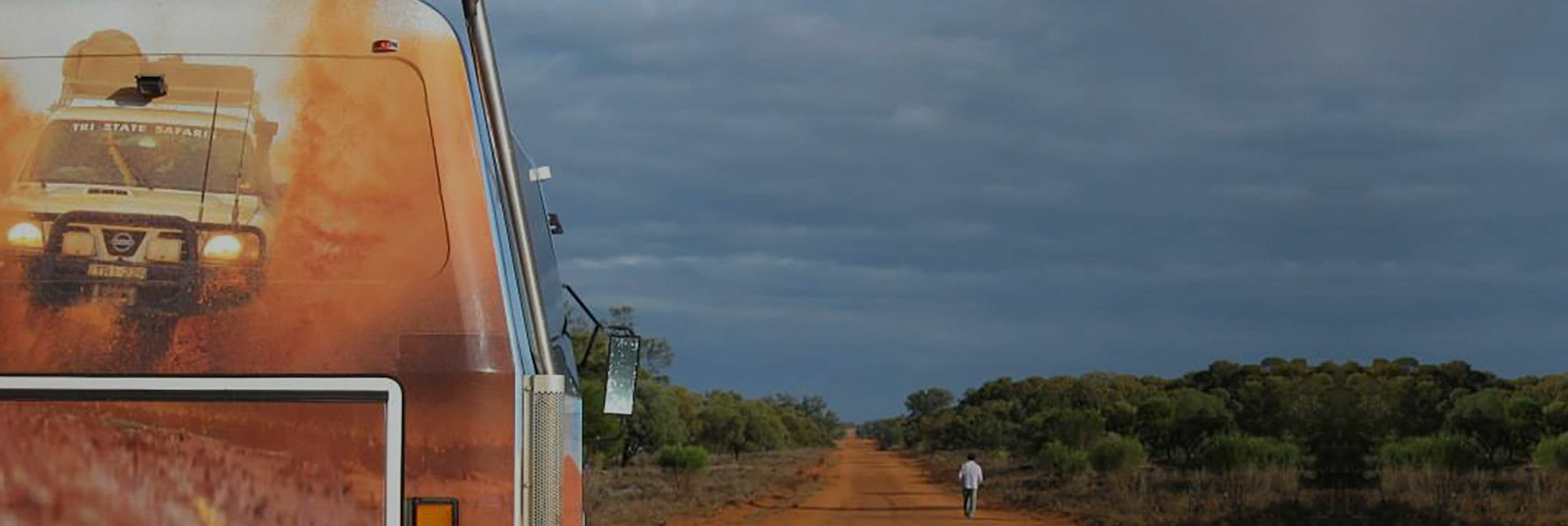Overland Adventures truck on an outback road under storm clouds