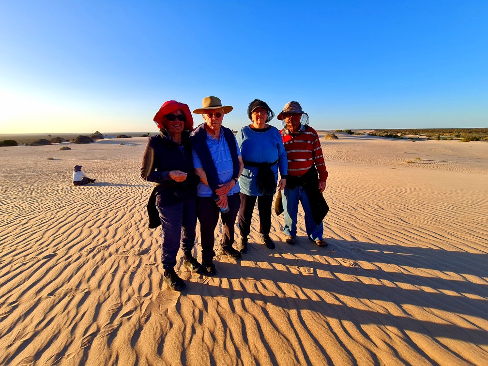 Small group of guests walking across rippled sand dunes at Mungo National Park