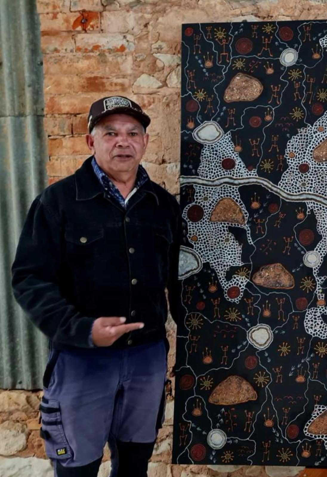 Eddy Harris, Barkandji cultural elder, beside an Aboriginal dot painting