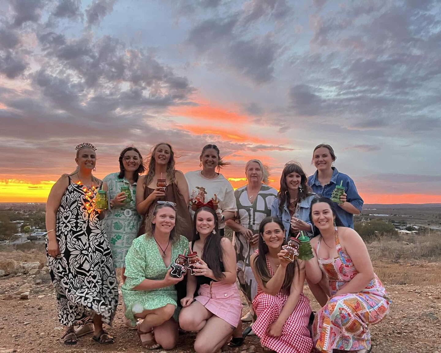 Group of women celebrating with drinks at sunset in the outback