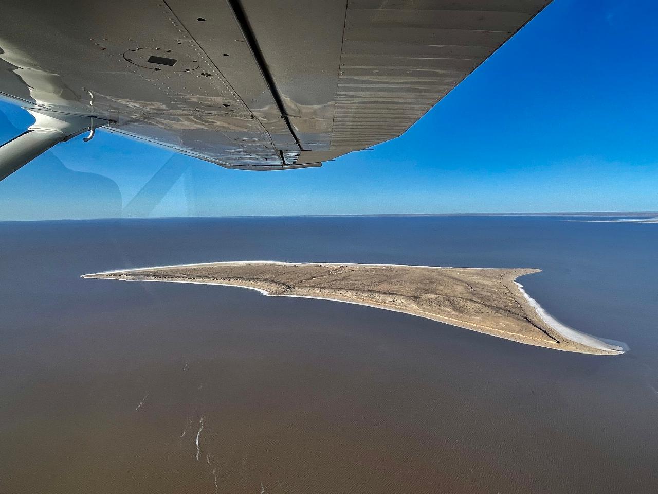 Sandy island in Lake Eyre seen beneath the wing of a scenic flight