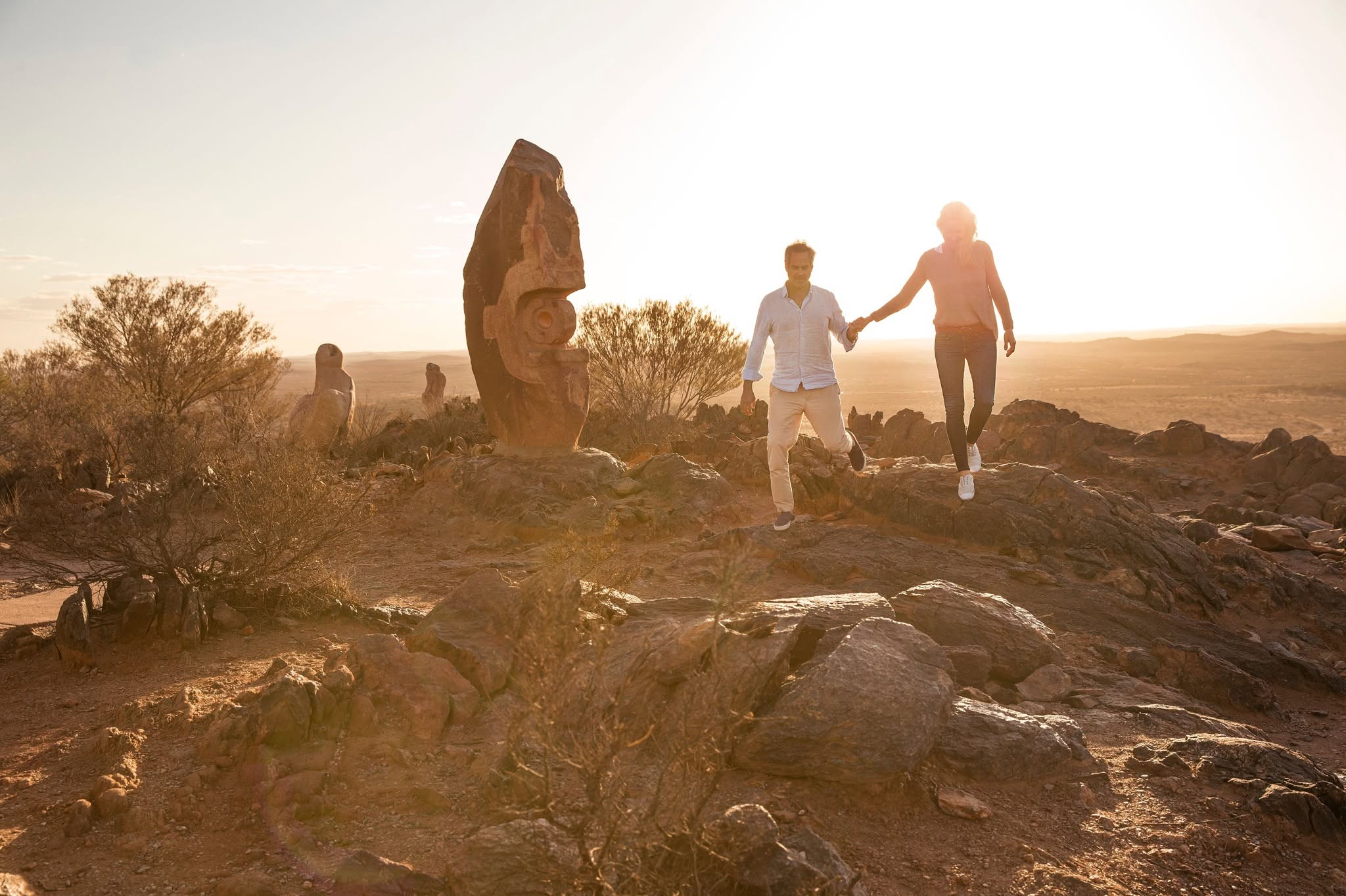 Couple walking hand in hand past a sculpture at the Living Desert at sunset