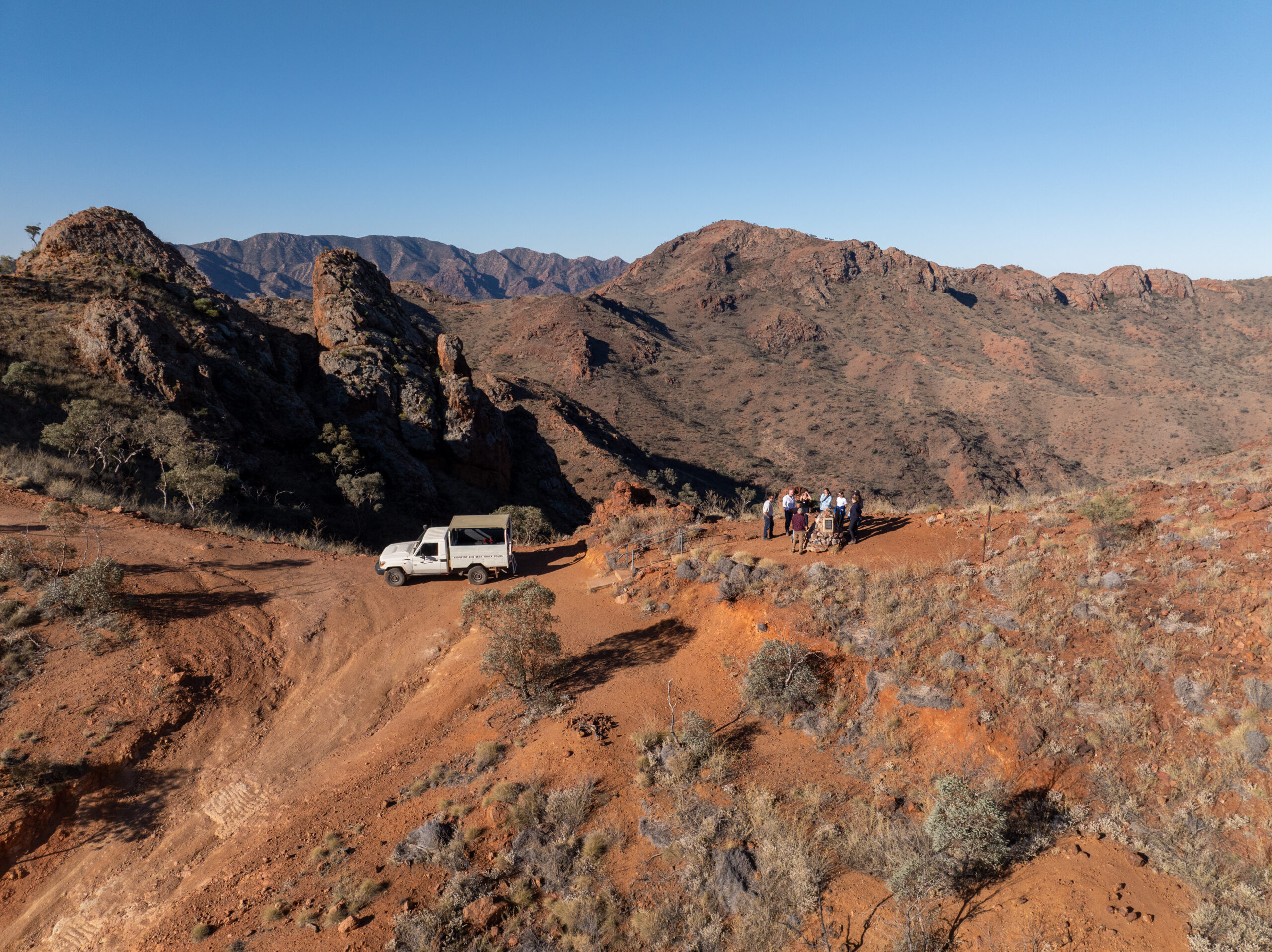 Tour vehicle on a ridge track among rugged red ranges