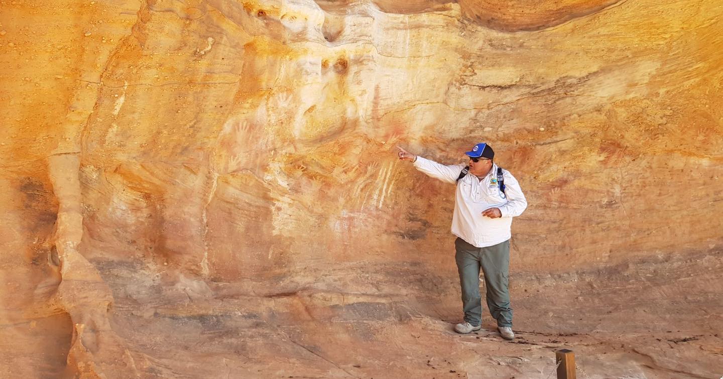 Guide standing beneath an ochre rock overhang at Mutawintji National Park