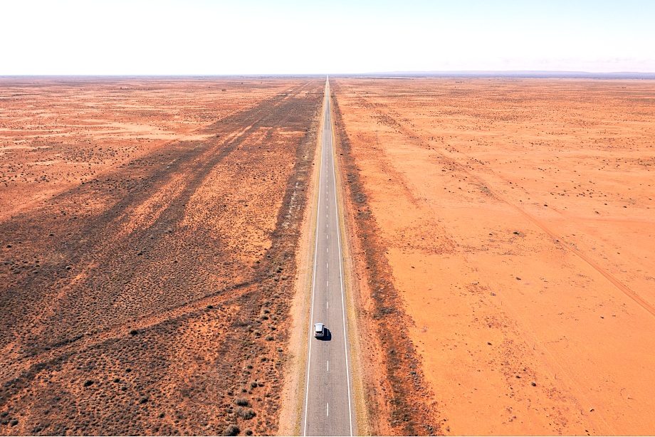 Aerial view of a straight outback highway through red plains