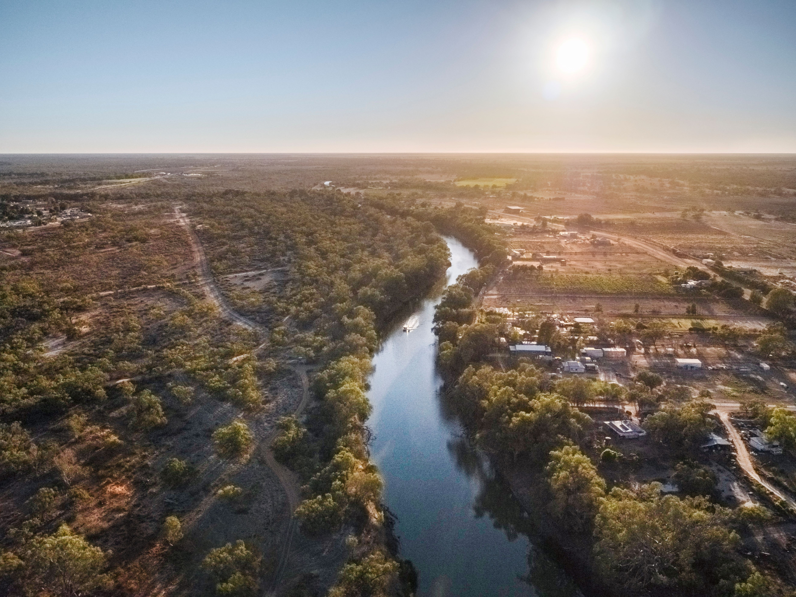 Aerial view of a river winding past an outback town at sunrise