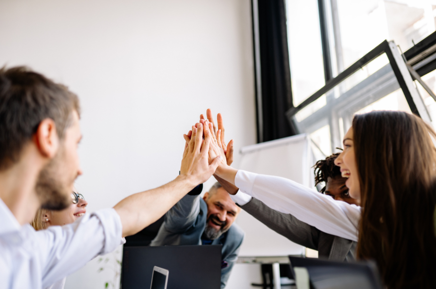 A team high-fiving around an office desk