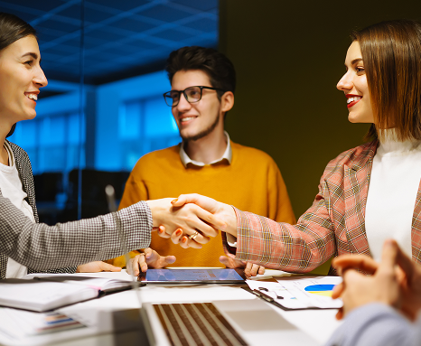 Team members shaking hands across a meeting table